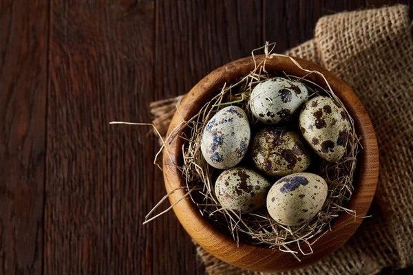 Bodegón rústico con huevos de codorniz en cubo, caja y tazón sobre una servilleta de lino sobre fondo de madera, enfoque selectivo — Foto de Stock