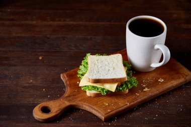 Kahvaltı Masası sandviç ve rustik arka plan, yakın çekim, seçici odak ahşap kesme tahtası üzerinde siyah kahve