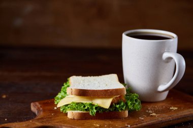 Kahvaltı Masası sandviç ve rustik arka plan, yakın çekim, seçici odak ahşap kesme tahtası üzerinde siyah kahve