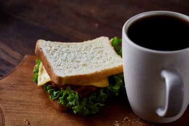 Kahvaltı Masası sandviç ve rustik arka plan, yakın çekim, seçici odak ahşap kesme tahtası üzerinde siyah kahve