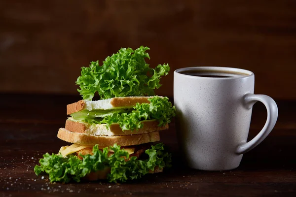 Πρωινό τραπέζι με σάντουιτς και μαύρο καφέ ρουστίκ ξύλινα φόντο, γκρο πλαν, επιλεκτική εστίαση — Φωτογραφία Αρχείου