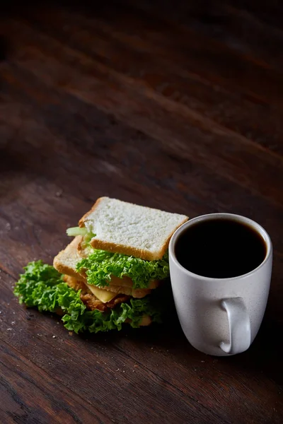 Frühstückstisch mit Sandwich und schwarzem Kaffee auf rustikalem Holzhintergrund, Nahaufnahme, selektiver Fokus — Stockfoto