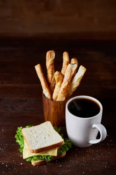 Breakfast table with sandwich and black coffee on rustic wooden background, close-up, selective focus — Stock Photo, Image