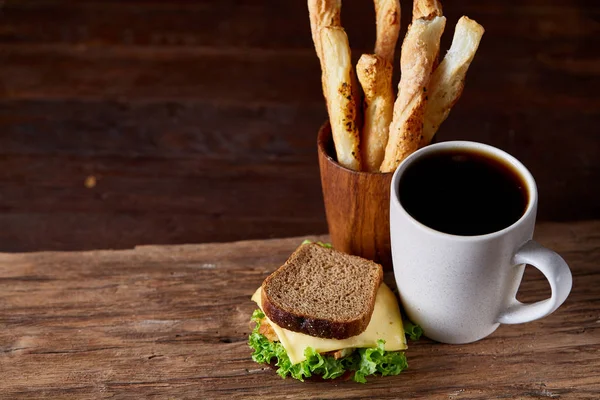 Coffee cup and breadsticks on an old wooden background, close-up, selective focus. — Stock Photo, Image