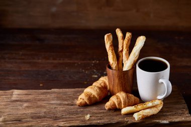 Kahve fincanı, breadsticks ve kruvasan bir eski ahşap arka plan, yakın çekim, seçici odak.
