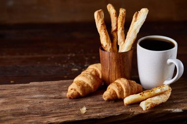 Kahve fincanı, breadsticks ve kruvasan bir eski ahşap arka plan, yakın çekim, seçici odak.