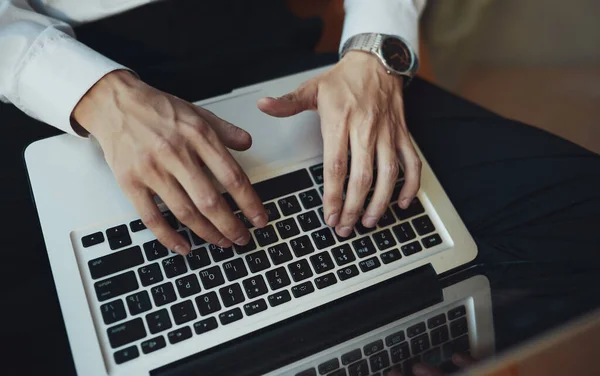 Dizüstü bilgisayar kullanan bir adamın elleri.