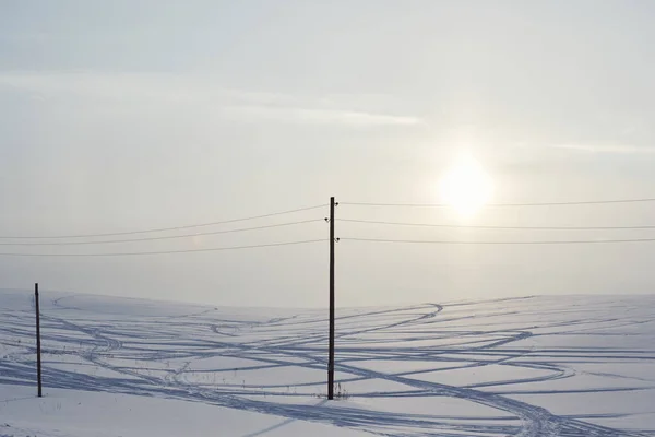 Geçen araba ve direklerden gelen izler kar tarlasını geçti.