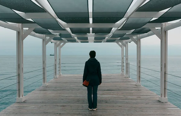 Tek başına düşünen ve denizi izleyen bir kadın.