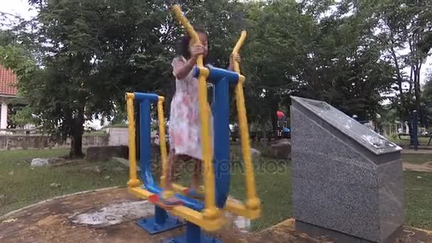 Una niña haciendo ejercicio en el equipo de gimnasio, bicicleta de hierro , — Vídeo de stock