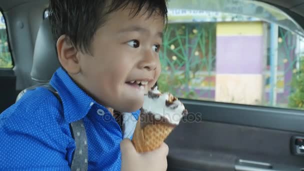 亚洲男孩一个冰淇淋蛋筒，在车上吃 — 图库视频影像