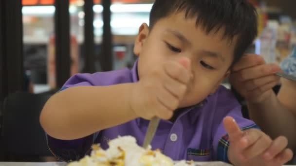 Niño sentado en la cafetería y comiendo helado — Vídeos de Stock