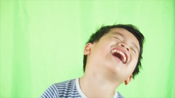 Kind lacht, kleiner asiatischer Junge lacht vor grünem Bildschirm. — Stockvideo