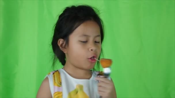 Linda niña comiendo bola de queso sobre fondo verde , — Vídeos de Stock