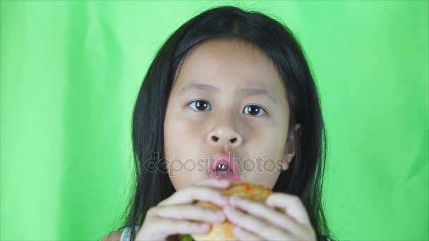 Asiatisk gullig flicka äta burgare på grön bakgrund, — Stockvideo
