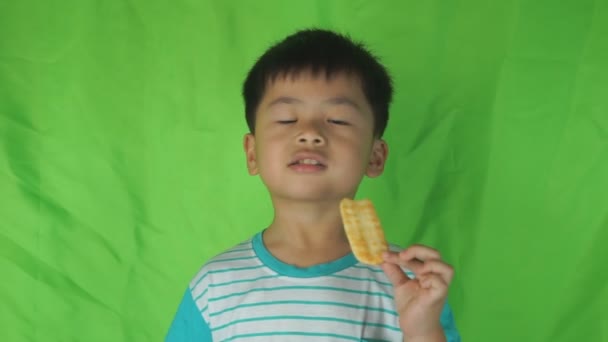 Netter Junge isst Kekse zu Hause auf grünem Hintergrund, — Stockvideo