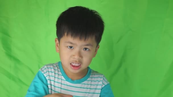 Lite asiatiska pojke banan höljet på grön bakgrund, — Stockvideo