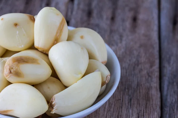 Peeled garlic in a cup on a wooden table. — Stock Photo, Image