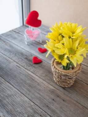 Bambu ahşap masa, bulanıklık kırmızı üzerinde yapılan vazoda sarı çiçek