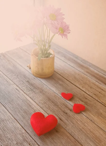 Red hearts on wooden table and pink flora in vase background, — Stock Photo, Image