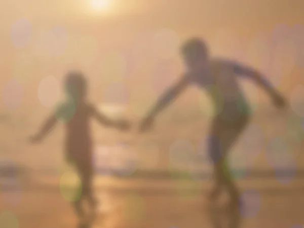 Rozmycie ojciec i córka grać na plaży o zachodzie słońca — Zdjęcie stockowe