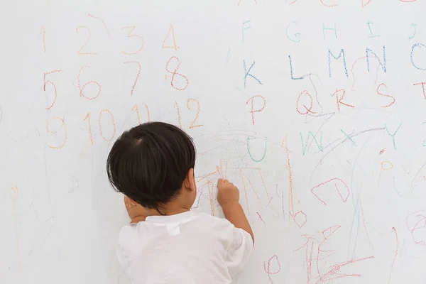 小さな男の子が壁の背景に書いて — ストック写真