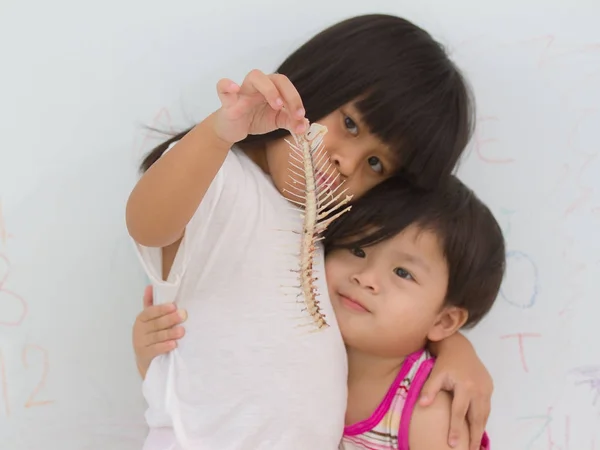 Arête de poisson à la main petite fille sur fond de mur — Photo