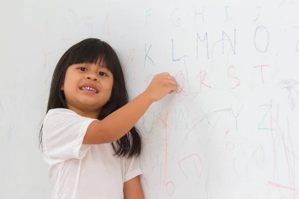Девушка пишет ABC на фоне стены — стоковое фото