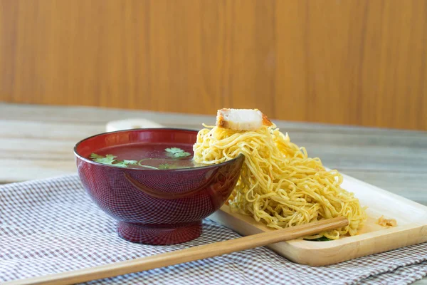 Żółty makaron na stronie kubek zupa w drewniany stół, — Zdjęcie stockowe