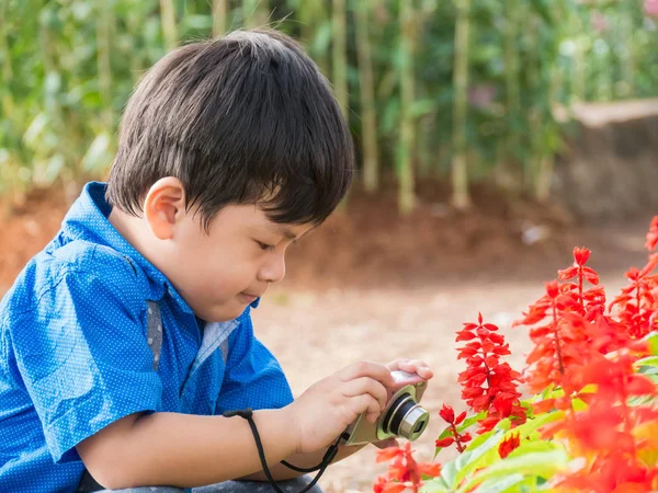 アジアの小さな男の子は庭の花にカメラを取る, — ストック写真