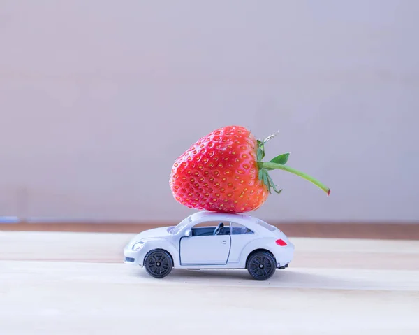 Erdbeere in weißem Spielzeugauto auf weißem Holzhintergrund, — Stockfoto