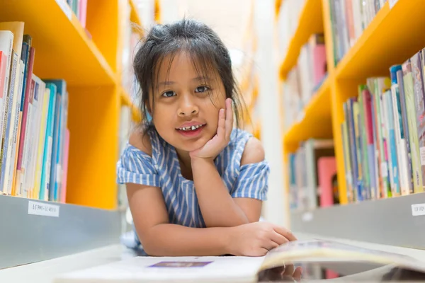 Ładna dziewczyna azjatyckich uśmiechający się w bibliotece na niewyraźne książki zadumany — Zdjęcie stockowe