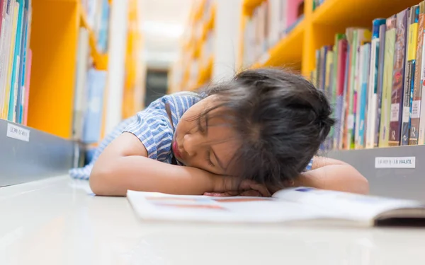 Pequena menina bonita dormindo no livro na biblioteca , — Fotografia de Stock