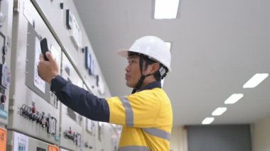 Mühendis düşük voltajlı motor kontrol merkezi kabin odasındaki elektrik sistemini kontrol ediyor ve izliyor.,