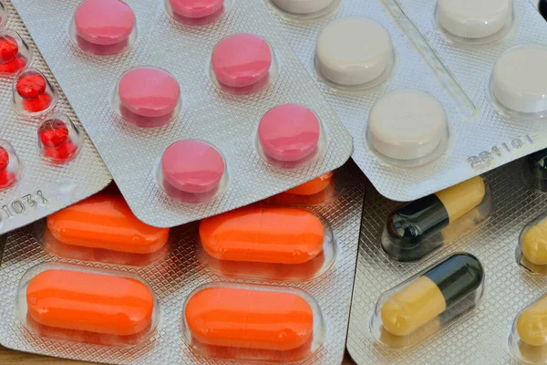 Vitamins and medicines in the form of tablets and capsules with a wooden background