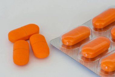 Üç turuncu tablet ve gri arka planda su toplayan bir tablet.