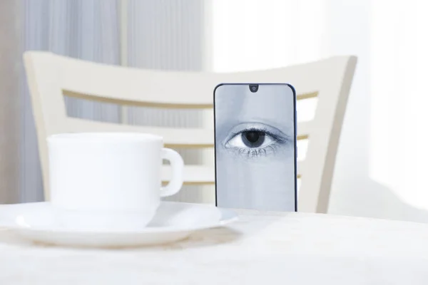 Akıllı telefon ekranındaki bir göz resmi masadan dışarı bakıyor.
