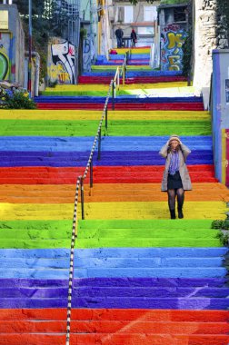 Woman is walking in the rainbow-colored stairs clipart