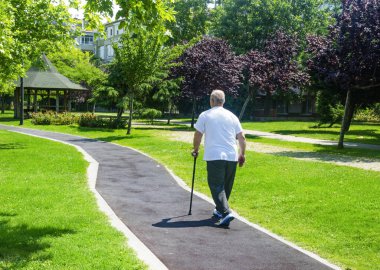 Yaşlı adam bastonla parkta yürüyüş