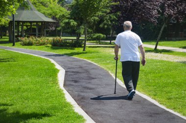 Yaşlı adam bastonla parkta yürüyüş