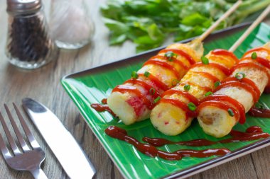 Omlet yuvarlama çubuğu yeşil muz yaprağı tabağında sokak yemeğiyle birlikte. 