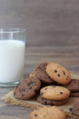 Taze sağlıklı süt ve ahşap masada bir yığın çikolata parçalı kurabiye..
