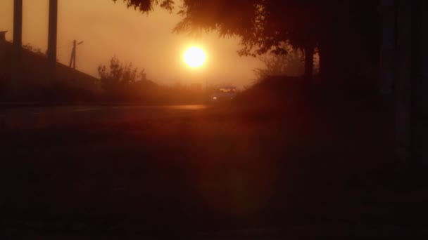 El coche cabalga sobre un fondo del sol naciente en una calle brumosa . — Vídeos de Stock