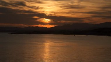 Günbatımı dağların arkasında. Denizin içinde yansıma