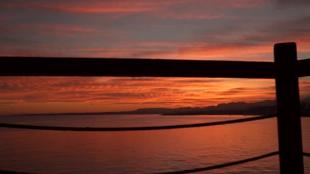 De bergen en de zee bij zonsondergang. Bekijken door hek — Stockvideo