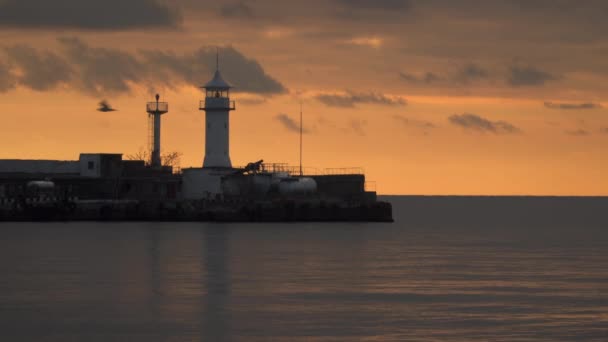 Φάρος στο λιμάνι ενάντια στον ουρανό στο ηλιοβασίλεμα — Αρχείο Βίντεο