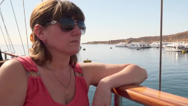 Młoda kobieta siedzi na pokładzie jachtu. — Wideo stockowe