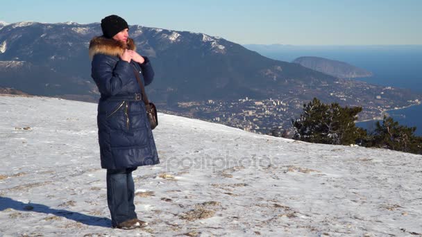 Kobieta stoi na szczycie góry w śniegu — Wideo stockowe