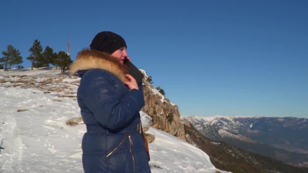 Mujer en la cima de montañas cubiertas de nieve hablando por teléfono — Vídeos de Stock