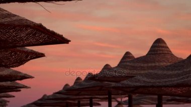 Gökyüzü gün batımında sahilde şemsiye